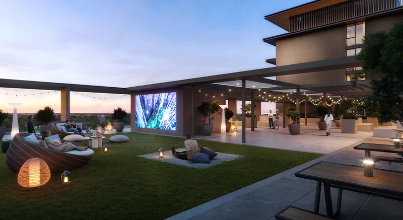 Render of the Parkwood rooftop terrace at dusk with an outdoor screen, lawn and seating
