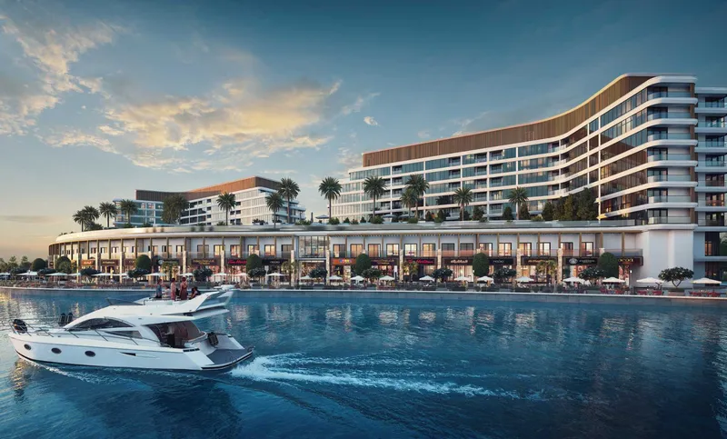 Pearlside Marina Residences curving along the canal on Sobha Siniya Island, with a yacht passing in front