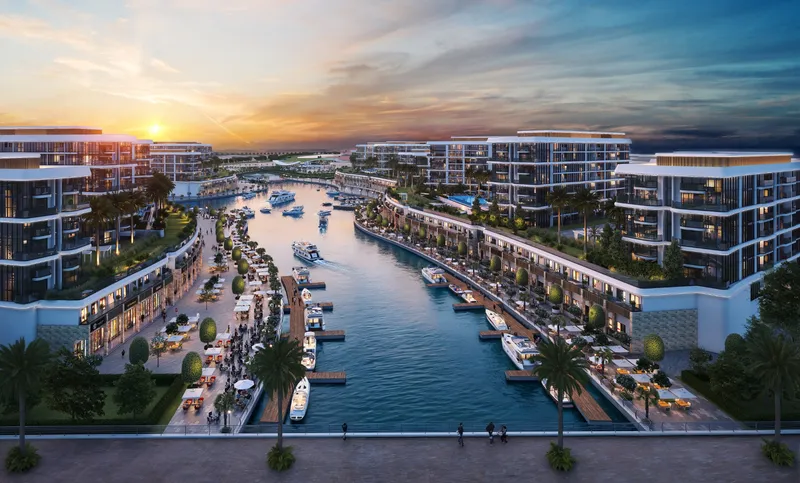 Aerial view of the marina canal at Sobha Siniya Island at sunset, lined with boats, promenades and apartment buildings