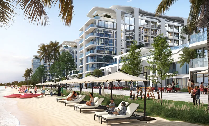 Pristine Beach Residences behind a row of sun loungers on the natural beach of Sobha Siniya Island
