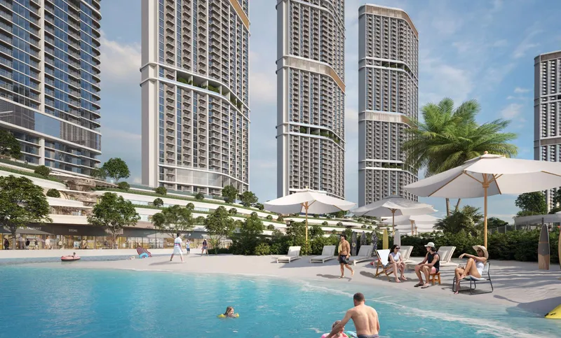 Sandy lagoon beach with sun loungers at the foot of the Riverside Crescent towers
