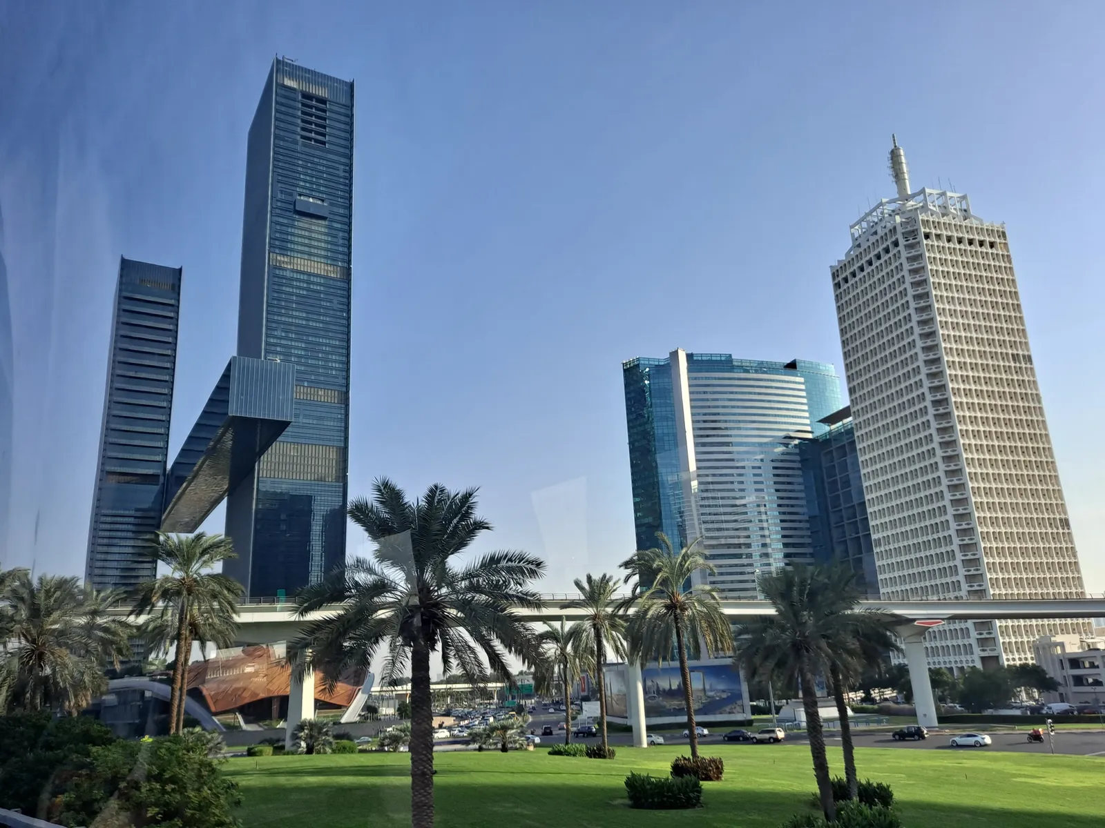 Office towers along Sheikh Zayed Road in Dubai with the Dubai Metro viaduct and palm trees in the foreground