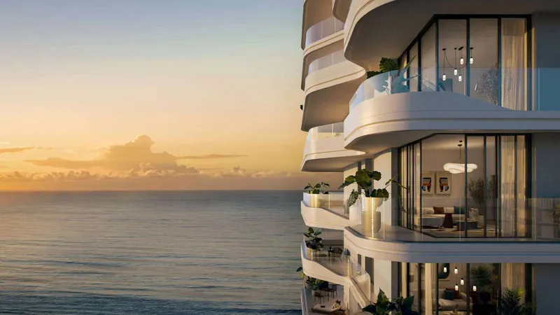 Curved balconies with glass balustrades at Rosso Bay Residences facing the sea at sunset
