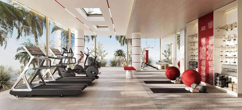 Gym with treadmills and exercise balls beside full-height windows and palm trees at Rosso Bay Residences