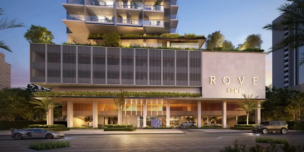Render of the Rove Home Downtown Dubai entrance at dusk, with a glazed ground-floor lobby below a louvred podium and landscaped terraces