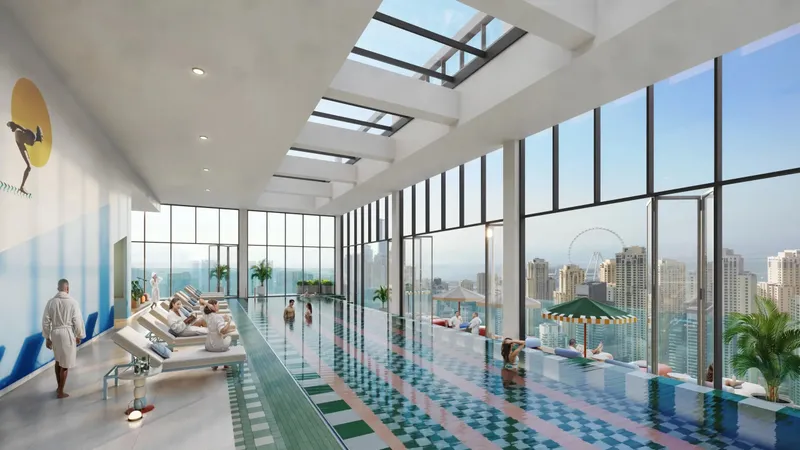 Glazed indoor infinity pool with loungers and city views at Rove Home Dubai Marina