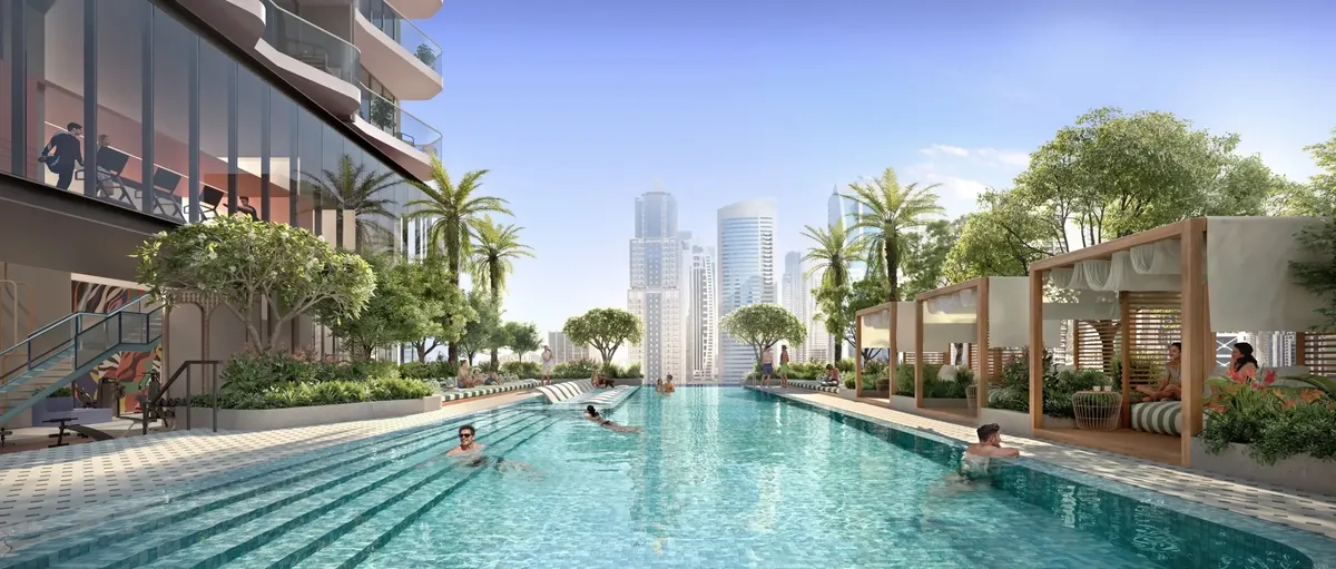 Swimmers in the long podium pool lined with palms and cabanas at Rove Home Dubai Marina