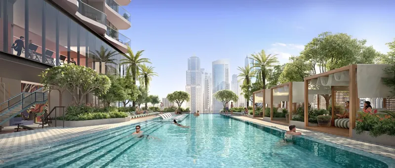 Swimmers in the long podium pool lined with palms and cabanas at Rove Home Dubai Marina