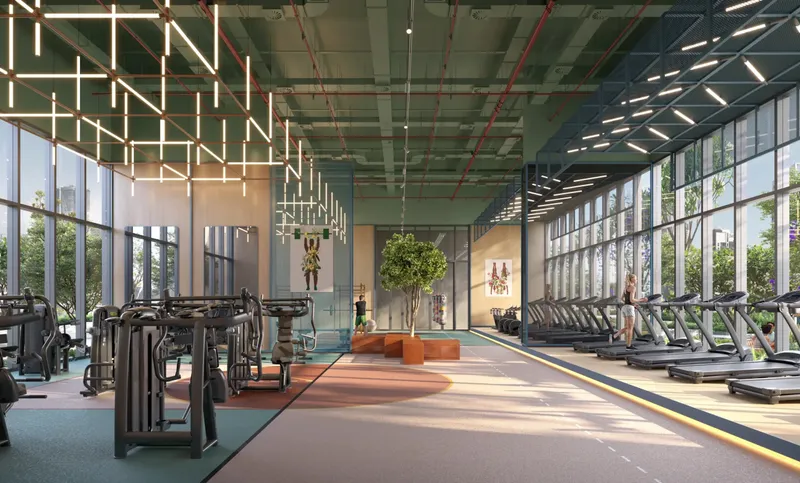 Indoor gym with weight machines and treadmills beside full-height windows