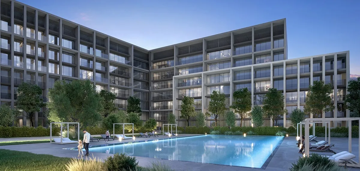 Evening render of the residents' swimming pool at Safa, Aljada, with sun loungers and the apartment buildings behind