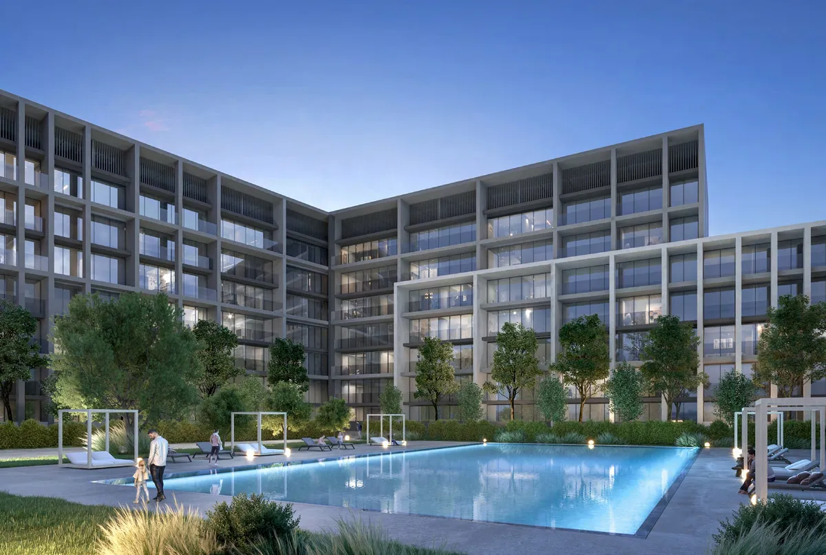 Evening render of the residents' swimming pool at Safa, Aljada, with sun loungers and the apartment buildings behind