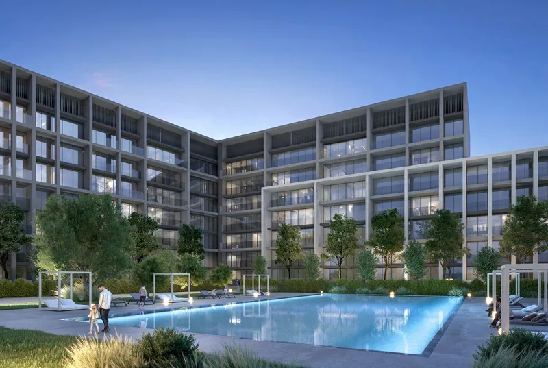 Evening render of the residents' swimming pool at Safa, Aljada, with sun loungers and the apartment buildings behind