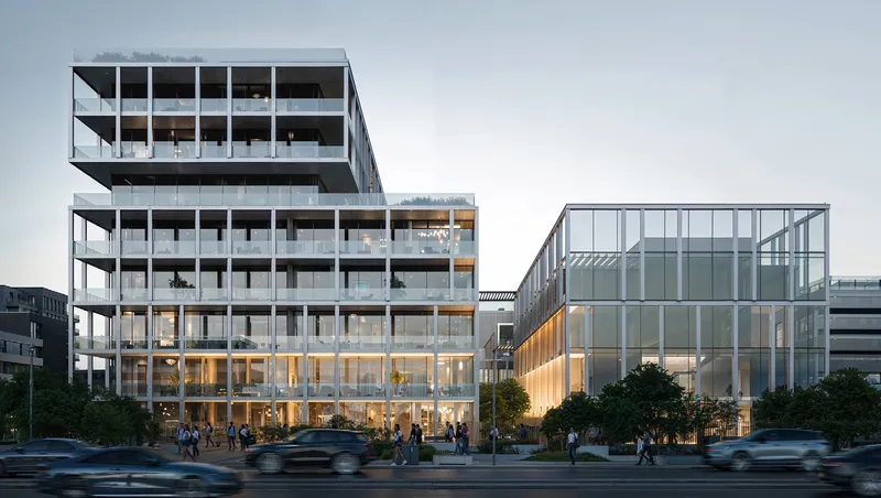 Street view of Sensi's glass-fronted residential and commercial buildings at dusk (developer render)