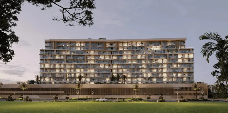 Front view of Serene Gardens II at dusk with lit apartments above the podium