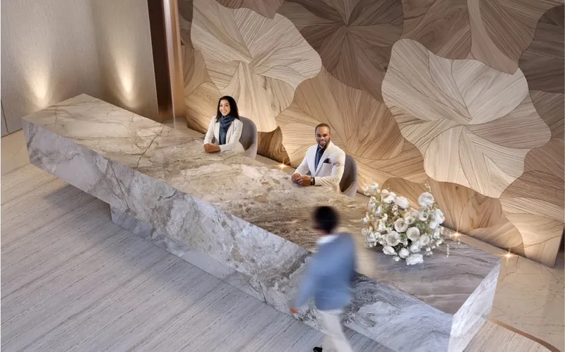 Interior render of the Sky Gate Tower lobby with a marble reception desk and a carved timber wall
