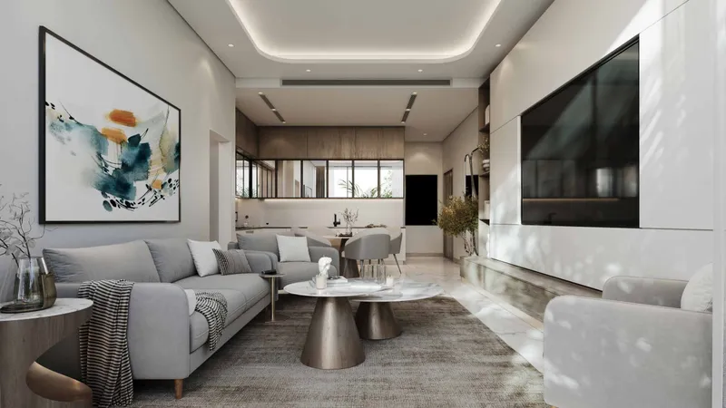 Living room with a grey sofa, wall-mounted television and an open kitchen beyond in a Skyhills Residences 3 apartment