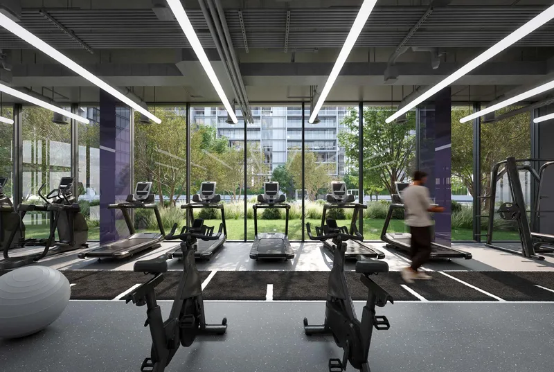 Render of the residents' indoor gym at The Gate, Aljada, with treadmills facing full-height windows onto the gardens