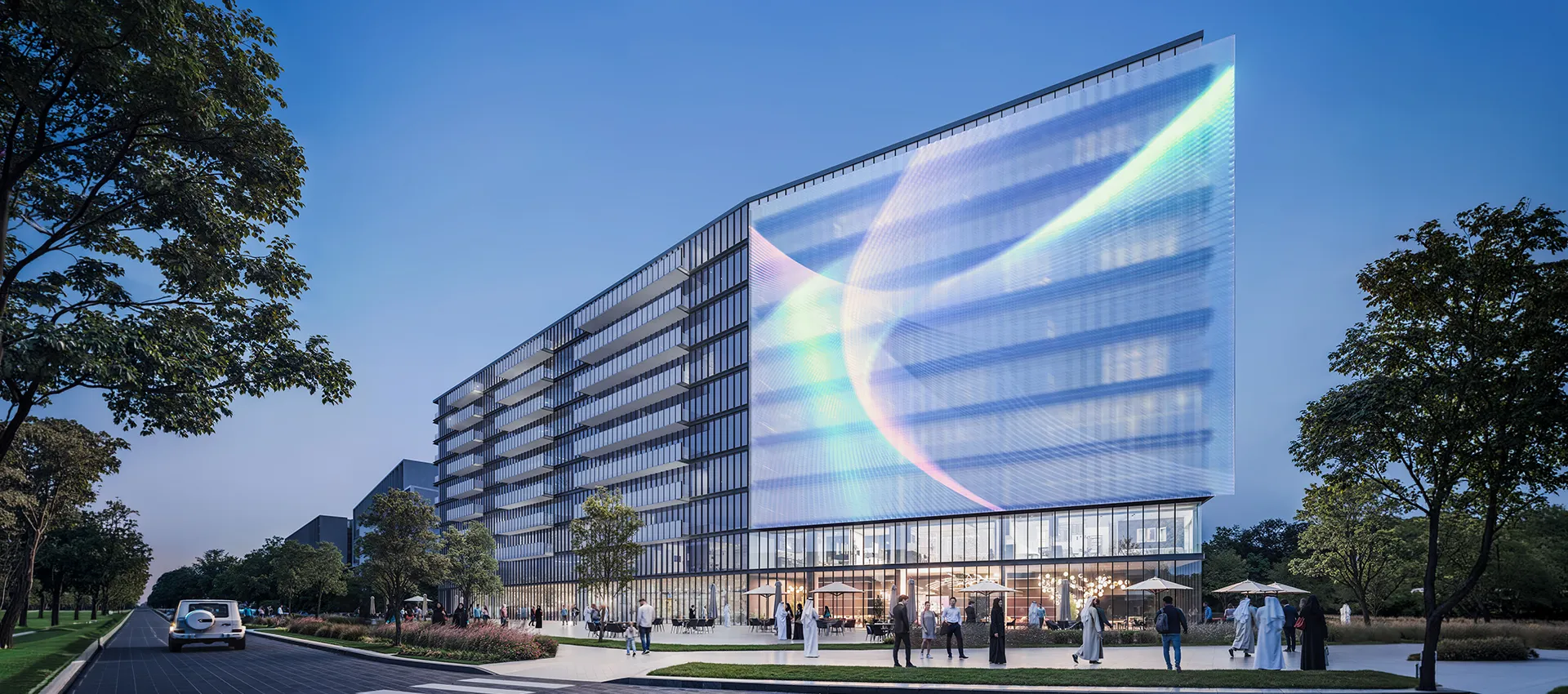 Dusk render of The Gate 6 at Aljada, a glass apartment building with an illuminated screen wrapping its corner above street-level cafes