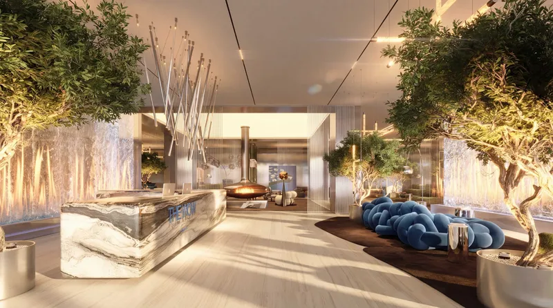 Arrival lobby with a stone reception desk, olive trees and blue lounge seating at The WOW Tower