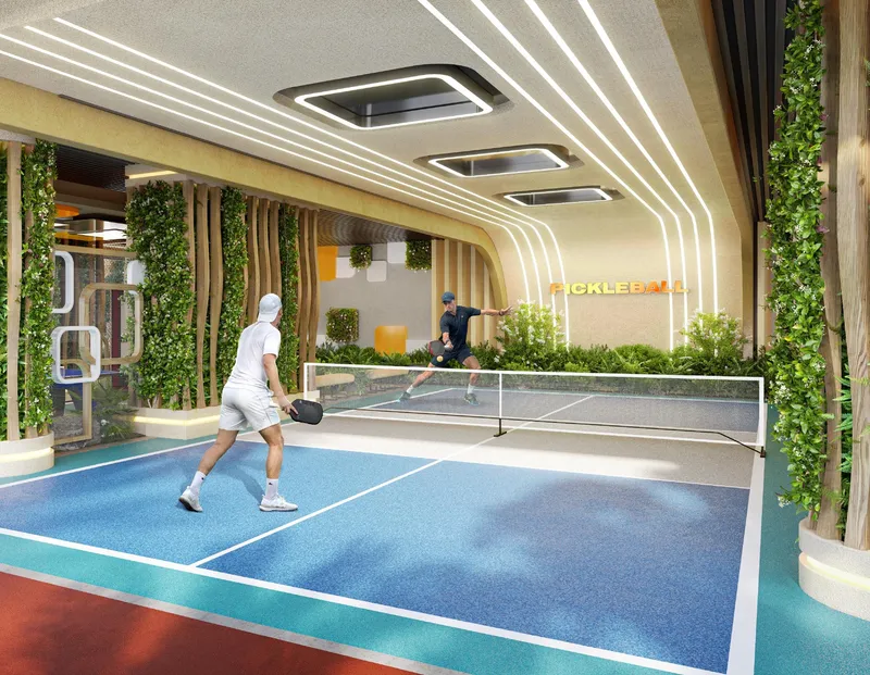 Two people playing on the blue pickleball court framed by planted walls