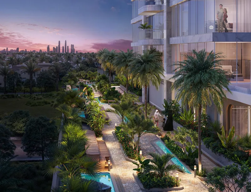 Landscaped garden with palm trees, lit paths and water channels beside the Vega tower at dusk