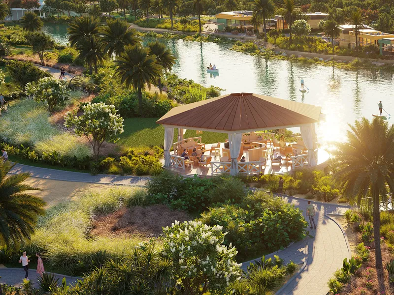 Pavilion with seating beside a lake and palm trees in the zen garden at DAMAC Hills 2