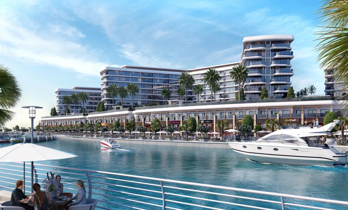 Yachtside Marina Residences above a row of waterfront shops on the canal of Sobha Siniya Island, with yachts passing