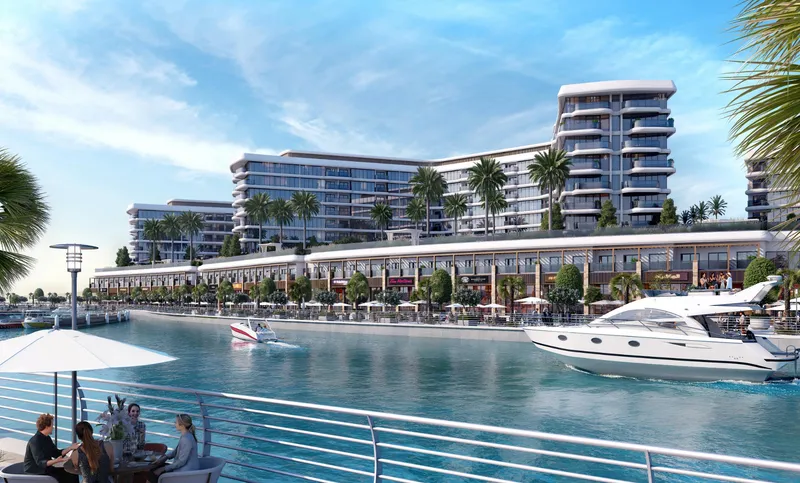Yachtside Marina Residences above a row of waterfront shops on the canal of Sobha Siniya Island, with yachts passing