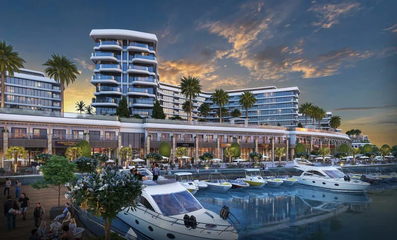 Yachtside Marina Residences at dusk with the waterfront shops lit and yachts moored in front